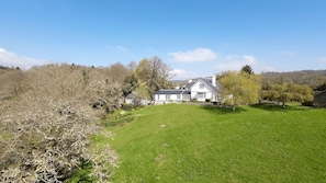A large house with a well-maintained lawn and trees in the background. - Higher Mapstone (Lustleigh)