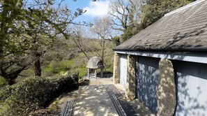 A pathway leading to a building with a stone facade and a covered area with a dome structure.