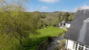 A residential property with a well-maintained lawn, a stone pathway, and a house with a steeply pitched roof. - Higher Mapstone (Lustleigh)