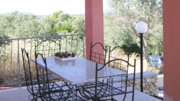 An outdoor patio with a table and chairs, a lamp post, and a view of trees and a car in the background. - 3-bedroom villa in fantastic Sassari with WiFi, AC (Sassari)