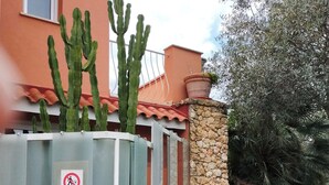 A building with a stone staircase, a metal fence with a no ball games sign, and cacti. - 3-bedroom villa in fantastic Sassari with WiFi, AC (Sassari)