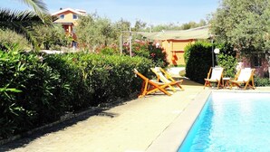 A pool area with lounge chairs, a clear sky, and a building in the background. - 3-bedroom villa in fantastic Sassari with WiFi, AC (Sassari)