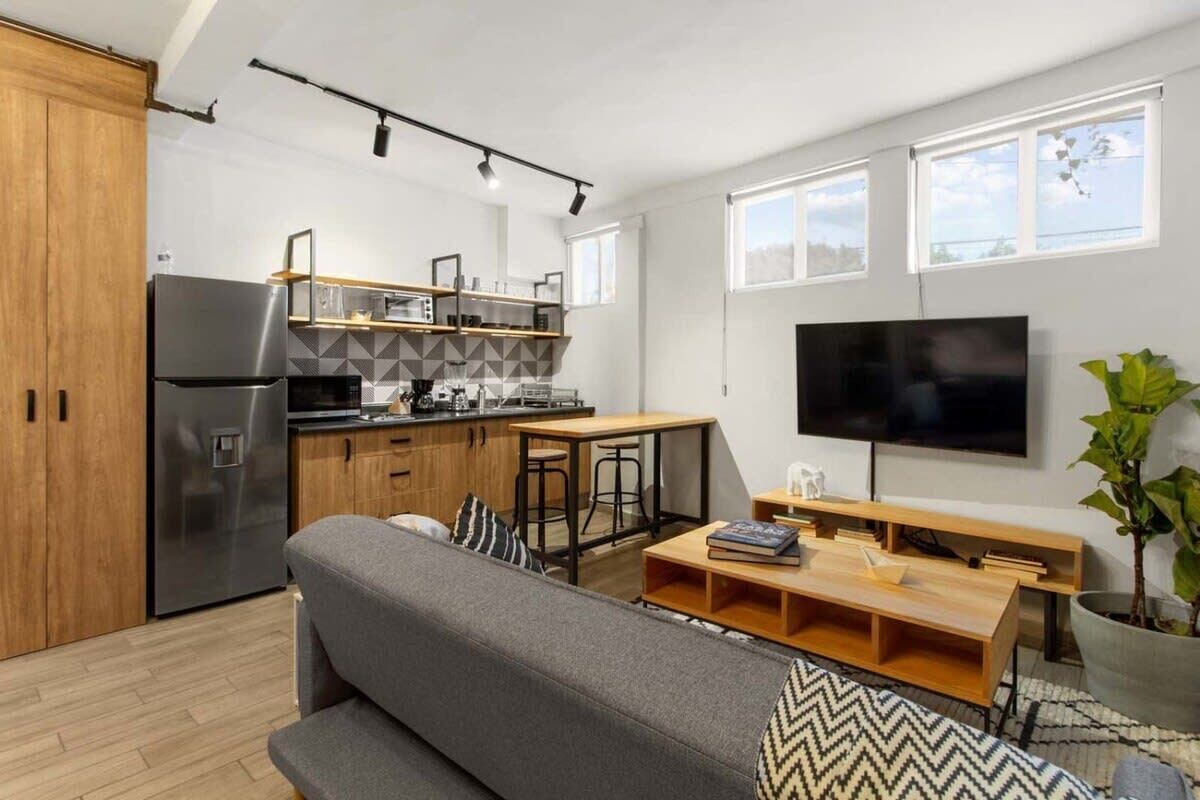 Een moderne keuken met een koelkast, houten kastjes en een eethoek met een tafel en stoelen.