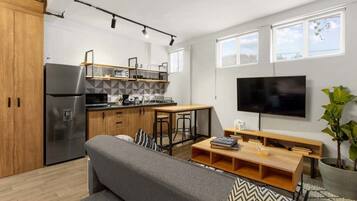 Een moderne keuken met een koelkast, houten kastjes en een eethoek met een tafel en stoelen.