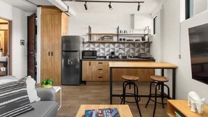 A compact kitchen with a central island, wooden cabinets, and a modern design. - MS Moderna Suite Arcos Hercules (Santiago de Querétaro)