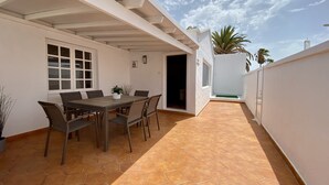 A covered patio with a hexagonal tile floor, a dining table with chairs, and a potted plant.