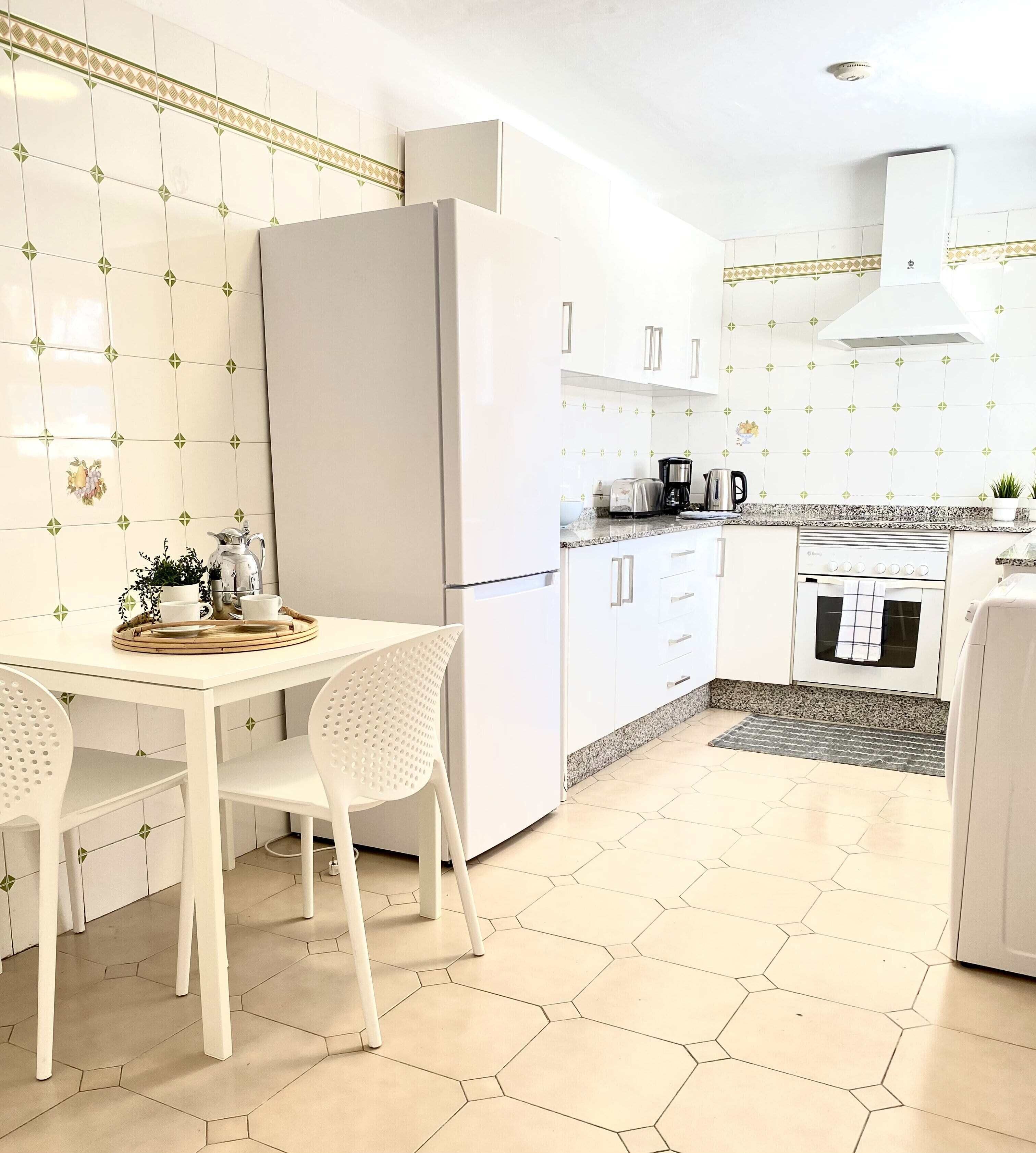 A modern kitchen with white cabinets, a refrigerator, a coffee maker, and a toaster.