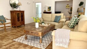 A living room with a sofa, a wooden cabinet, a coffee table, and a patterned rug.