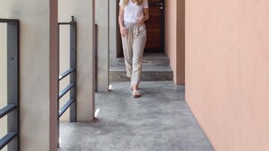 Un corridoio con pavimento in cemento e pareti beige, che termina con una porta in legno.