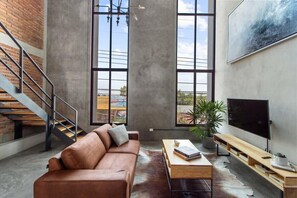 A spacious living room with a leather sofa, a coffee table, and a TV. A staircase and large windows are visible. - +MS +Lujoso Loft +Inmejorable ubicación +Arcos (Santiago de Querétaro)