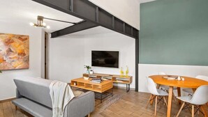 A modern living room with a sofa, coffee table, and dining table. - +MS +Cómoda Suite +Hércules (Santiago de Querétaro)