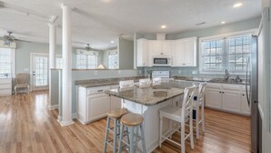 A spacious kitchen with a central island, white cabinetry, and a large window providing natural light. - Skipper's Hideout | Ocean Views + Walk to Beach! (North Topsail Beach)