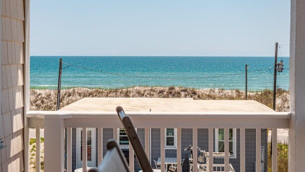 A balcony with a view of the ocean, a wooden deck, and a house in the background. - Skipper's Hideout | Ocean Views + Walk to Beach! (North Topsail Beach)
