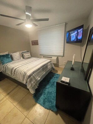 A bedroom with a bed, a ceiling fan, a TV, a heater, and a window with blinds. - 3 Bedrooms Apt. close to main beaches/ attractions (Río Grande)