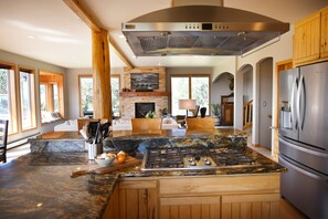 A spacious kitchen with a large island, a built-in stove, and a stainless steel refrigerator. - Escape to Your Family Retreat: Outdoor Adventures & Hot Tub Await! (Fairplay)
