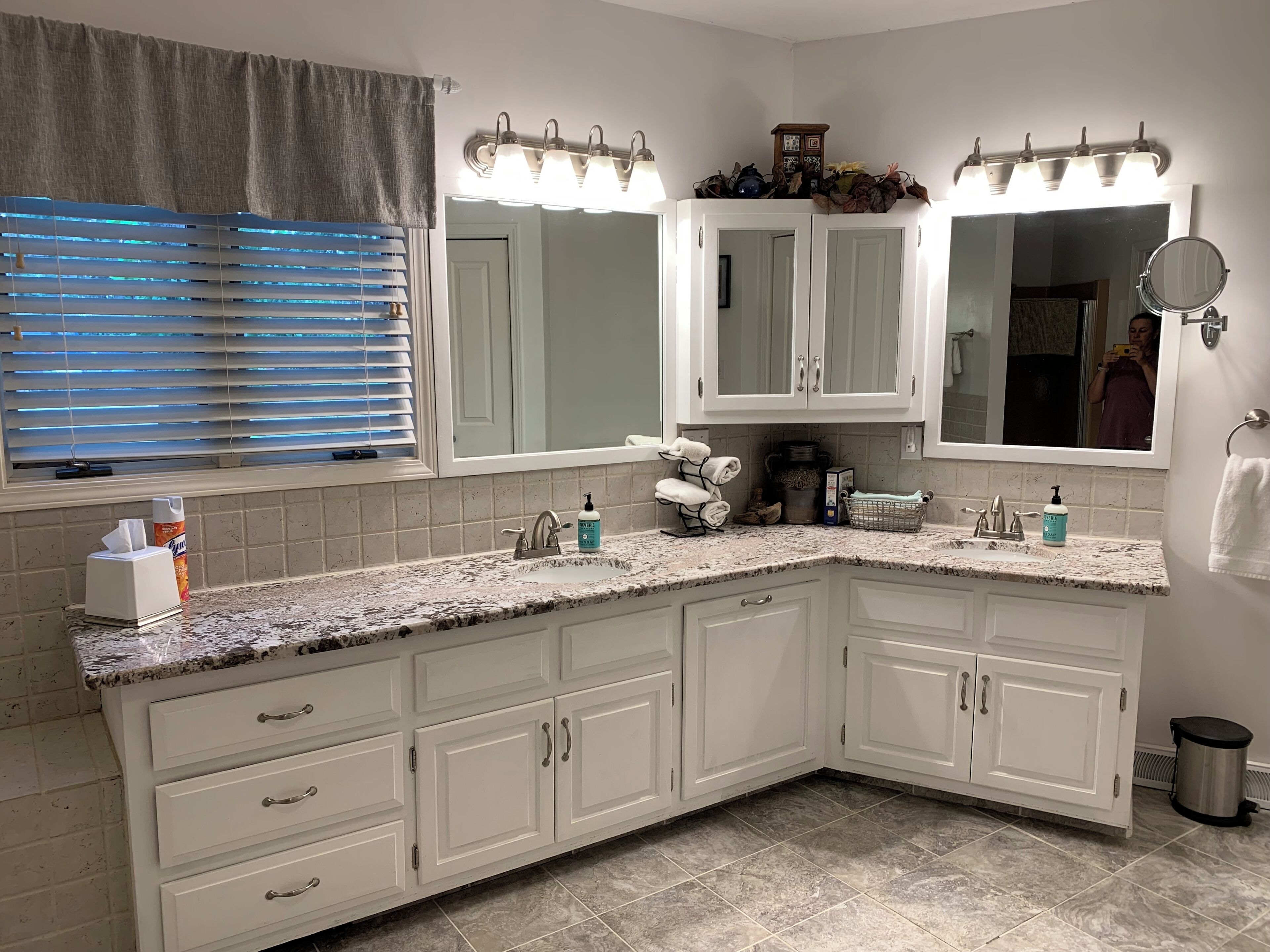 A bathroom with a large vanity, a mirror, and a sink. There are towels and toiletries on the counter.
