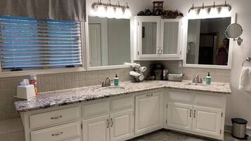 A bathroom with a large vanity, a mirror, and a sink. There are towels and toiletries on the counter.