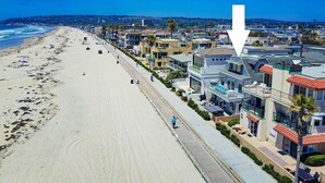 Et hotel ved stranden med en lang, sandet strand, en sti for fodgængere og moderne arkitektur.
