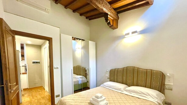 Ein Hotelzimmer mit einem Bett, einem Spiegel, einem Kleiderschrank und einer Holzzieldecke.