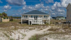 Une maison située en bord de mer, dotée d’un balcon et d’une terrasse couverte.