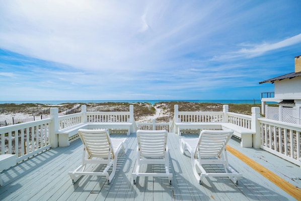 Una terraza con sillas blancas y vista a la playa.