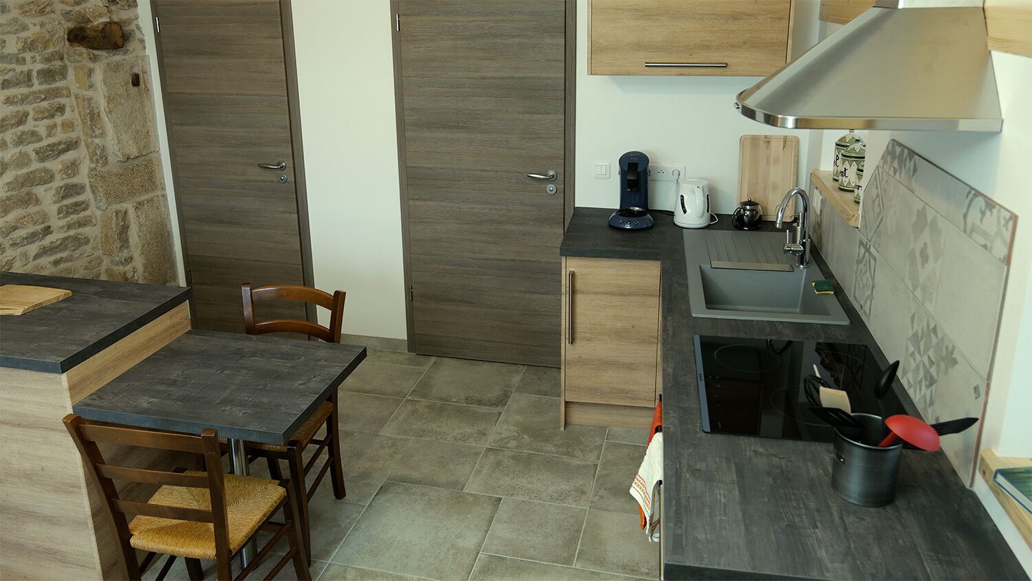 A compact kitchen with a dark countertop, wooden cabinets, a sink, and a stove.