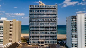 Un hôtel de grande hauteur doté de nombreux balcons, offrant une vue sur la plage et disposant d’un parking.