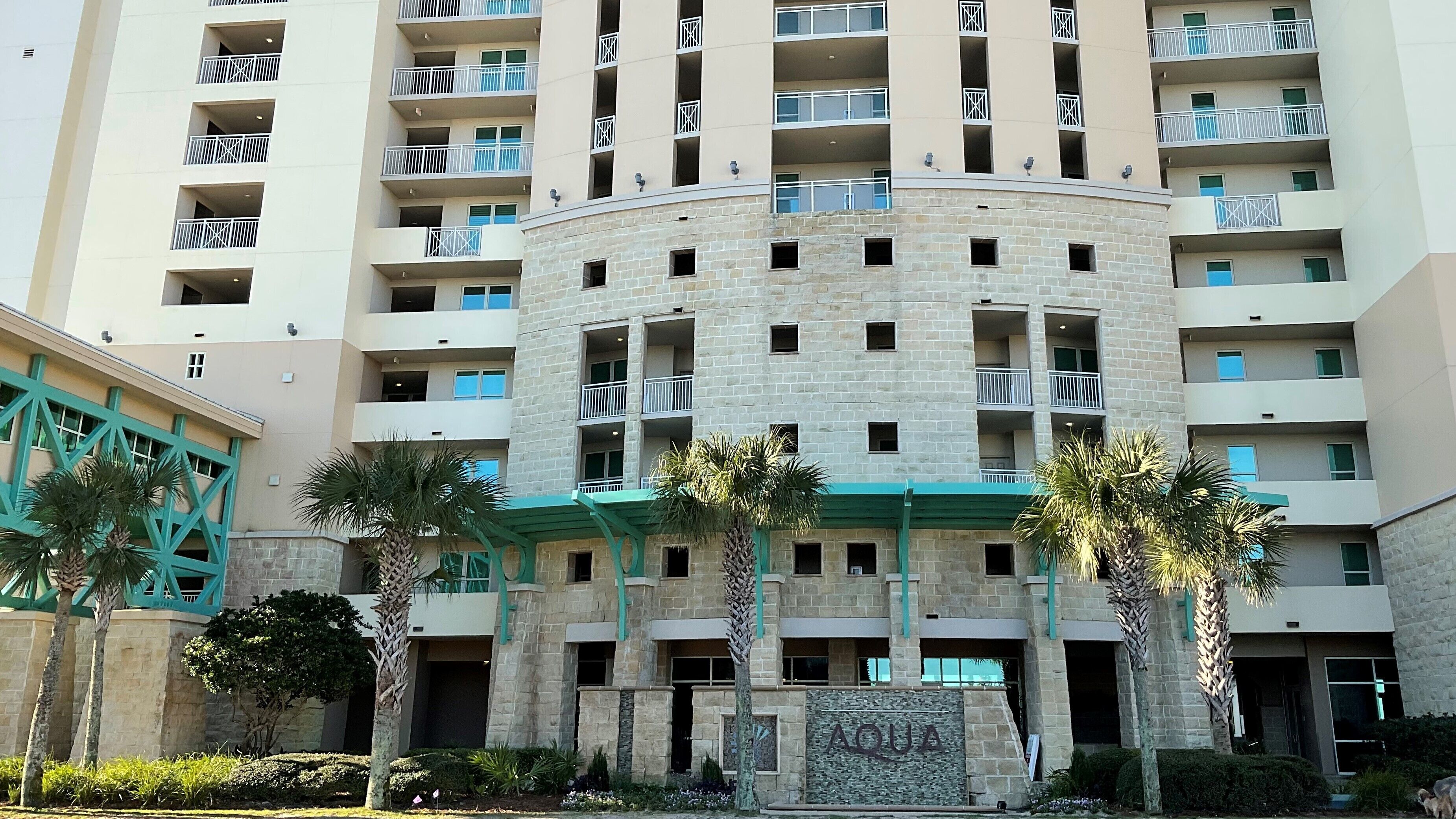 Ein mehrstöckiges Hotel mit Steinverkleidung, Balkonen und einer grünen Markise.