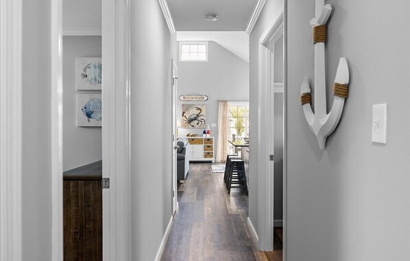 A hallway with a wooden floor, white walls, and a sign reading "BEACH HOUSE". - 3 BR 2 BA Home in Montego Bay - Community Pool (Ocean City)