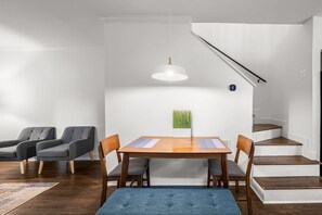 Una zona de dinar moderna amb taula de fusta, cadires tapissades de gris i llum penjant.