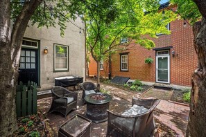 An outdoor patio with wicker furniture, a fire pit, and a brick wall. - Quiet Fells Point Home Just off the Main Street (Baltimore)
