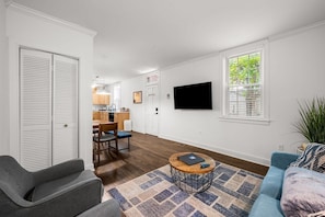 Ein Wohnzimmer mit einer Couch, einem Couchtisch und einem an der Wand befestigten Fernseher.