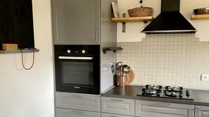 A modern kitchen with grey cabinets, a Bosch oven, a gas stove, and a tiled backsplash.