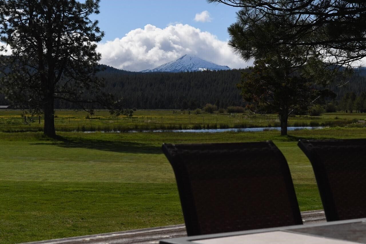 A view of a mountain with a lake and trees in the foreground.