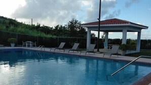 A rectangular swimming pool with a tiled edge, a covered pavilion with a red roof, and lounge chairs along the poolside. - 3 Bedrooms Apt. close to main beaches/ attractions (Río Grande)