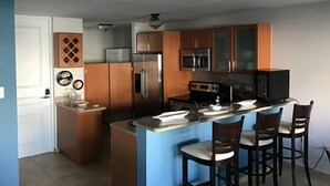 A modern kitchen with wooden cabinets, stainless steel appliances, and a central island with bar stools. - 3 Bedrooms Apt. close to main beaches/ attractions (Río Grande)