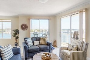 Enjoy a serene view of the water from this stylish living room with a sofa, armchair, and coffee table.