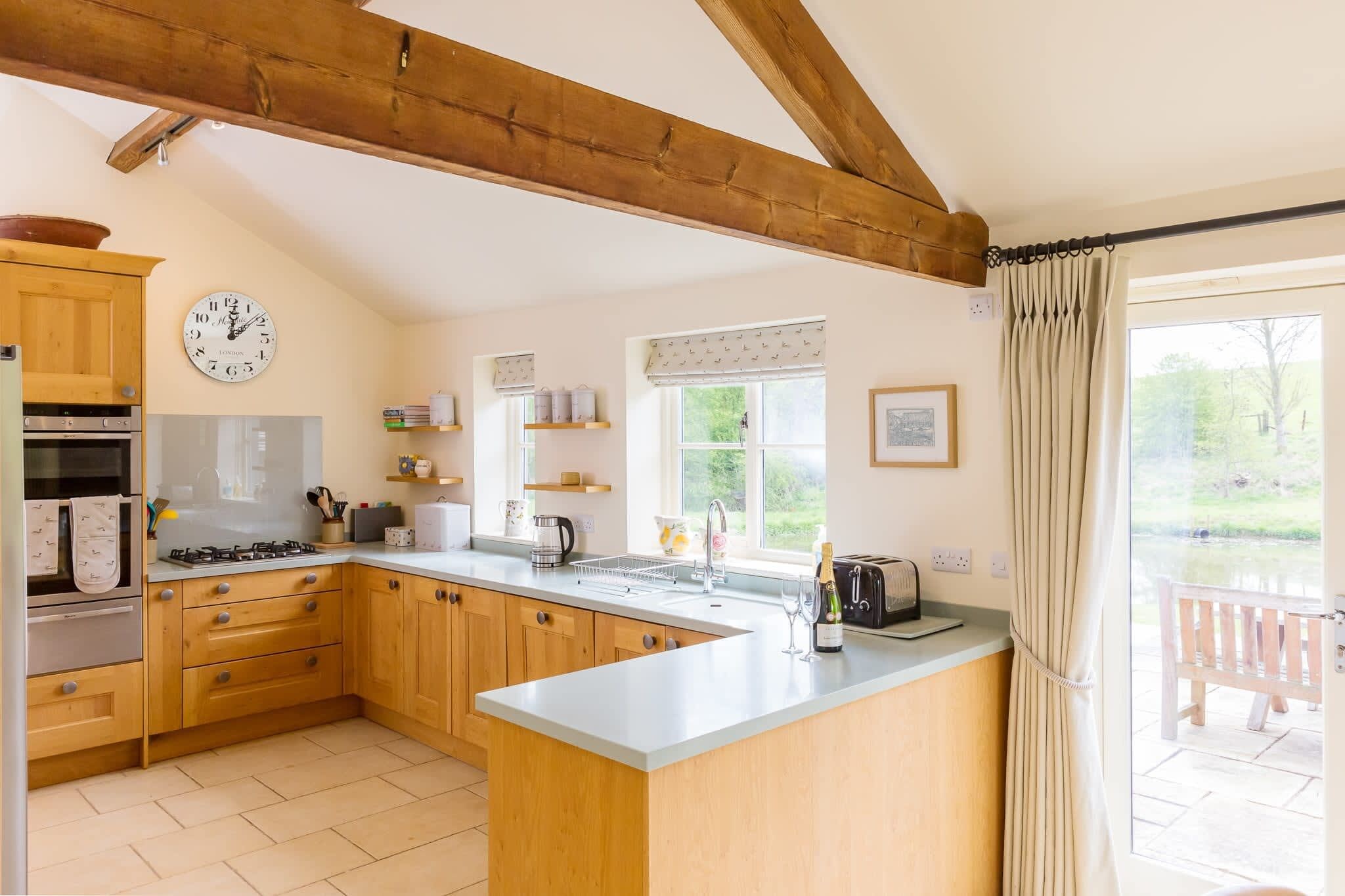 A kitchen with wooden cabinets, a gas stove, a sink, and a window with curtains.