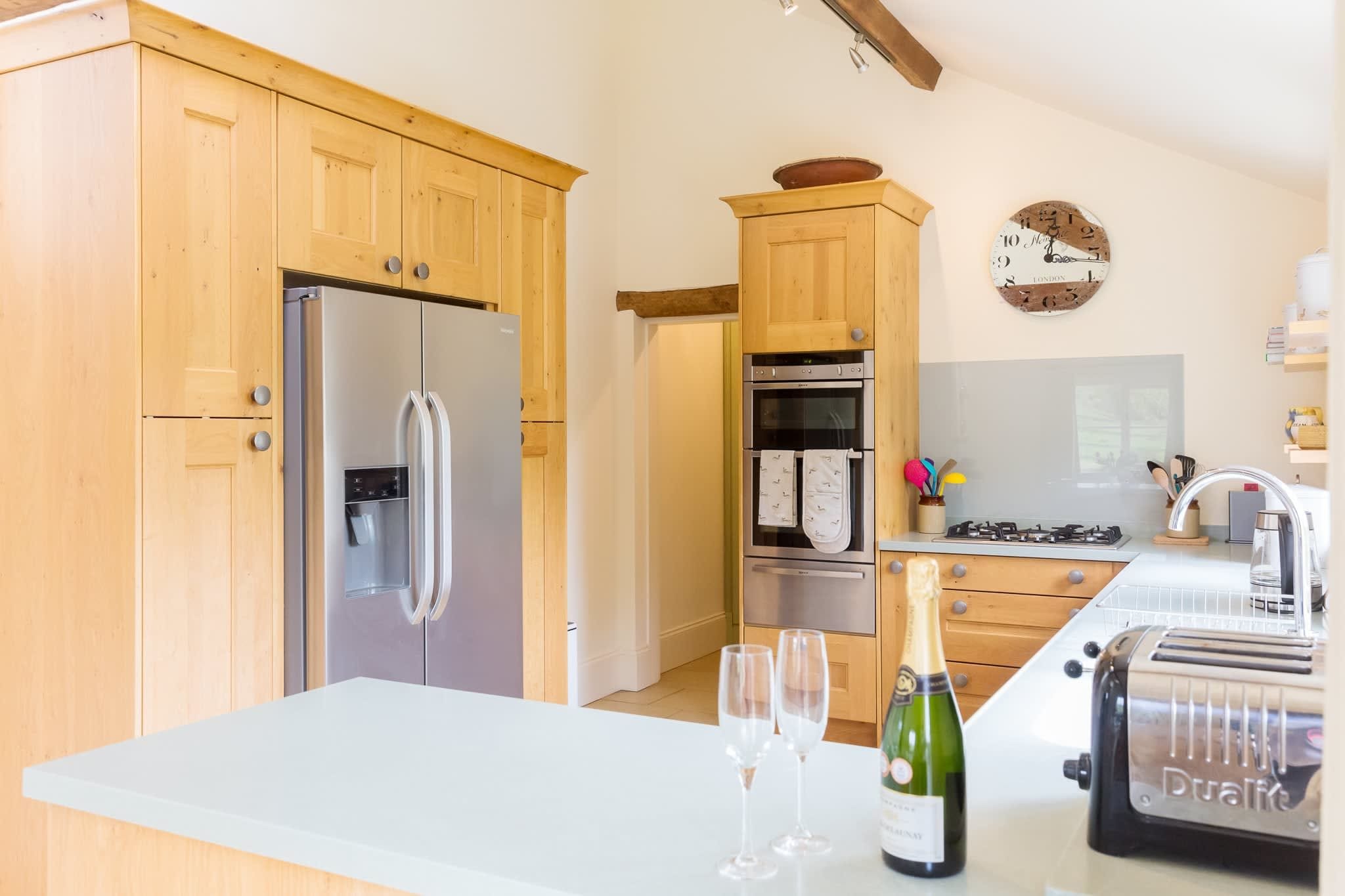A modern kitchen with wooden cabinets, stainless steel appliances, and a white countertop.