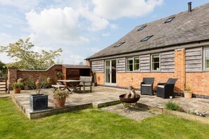 A brick house with a patio area, outdoor seating, and a fire pit. - Chater Barn (Leicester)