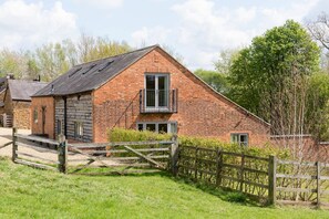 A brick house with a balcony, a wooden gate, and a grassy yard. - Chater Barn (Leicester)
