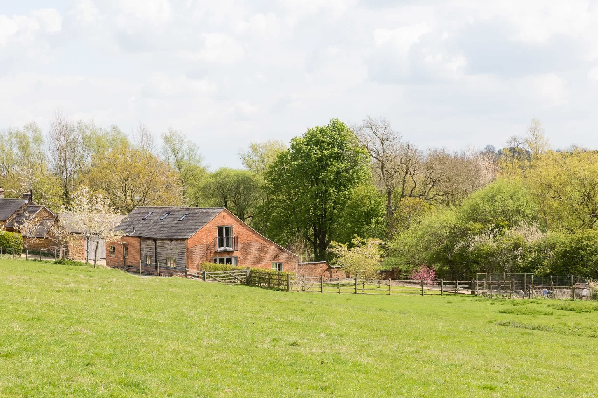 A brick house with a sloped roof and a fenced yard.