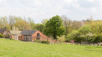 A brick house with a sloped roof and a fenced yard.