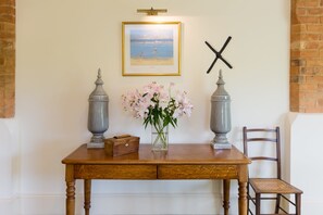 A wooden table with two gray vases, a vase with pink flowers, and a framed painting on the wall.