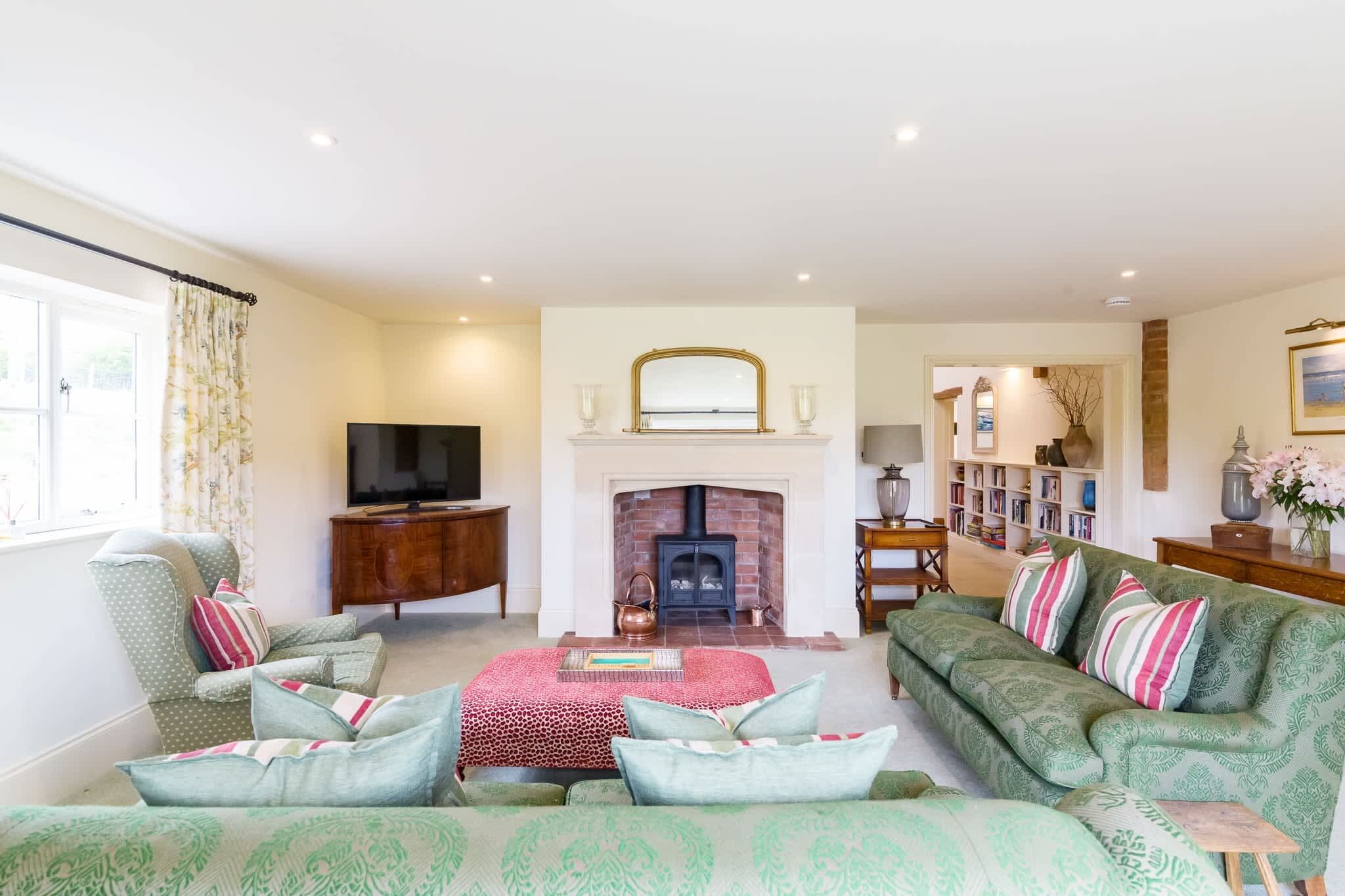 A living room with a fireplace, a television, a sofa, and a bookshelf.