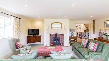 A living room with a fireplace, a television, a sofa, and a bookshelf.