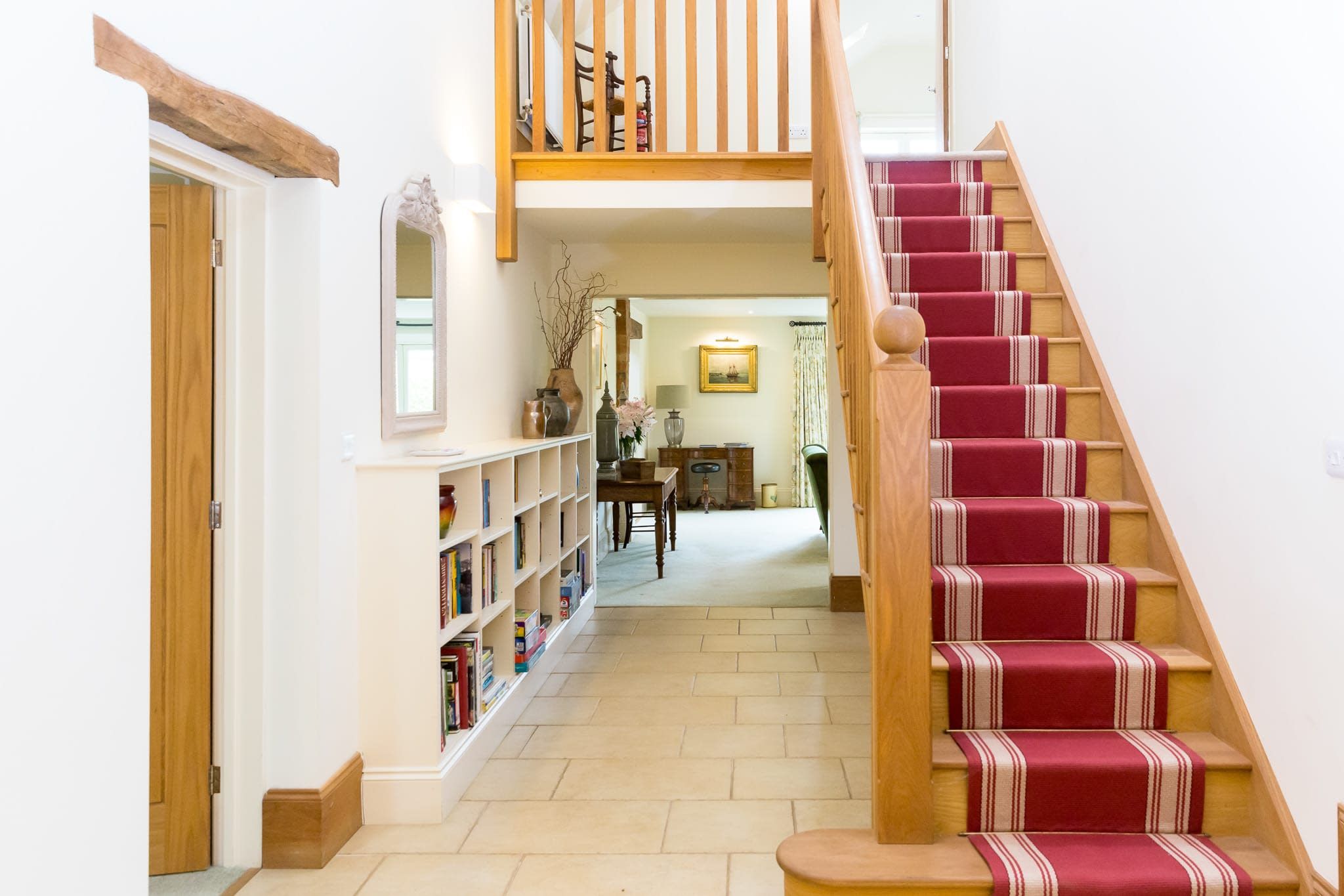 A staircase with a red carpet and wooden balusters leading to an upper floor.