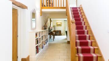 A staircase with a red carpet and wooden balusters leading to an upper floor.