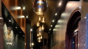 Un vestíbulo de hotel con suelo de mármol, una recepción y una escalera que sube a los pisos superiores.
