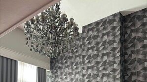 Una sala de estar moderna con un muro de patrón geométrico, un sofá capitonado, una mesa de centro redonda y una araña.